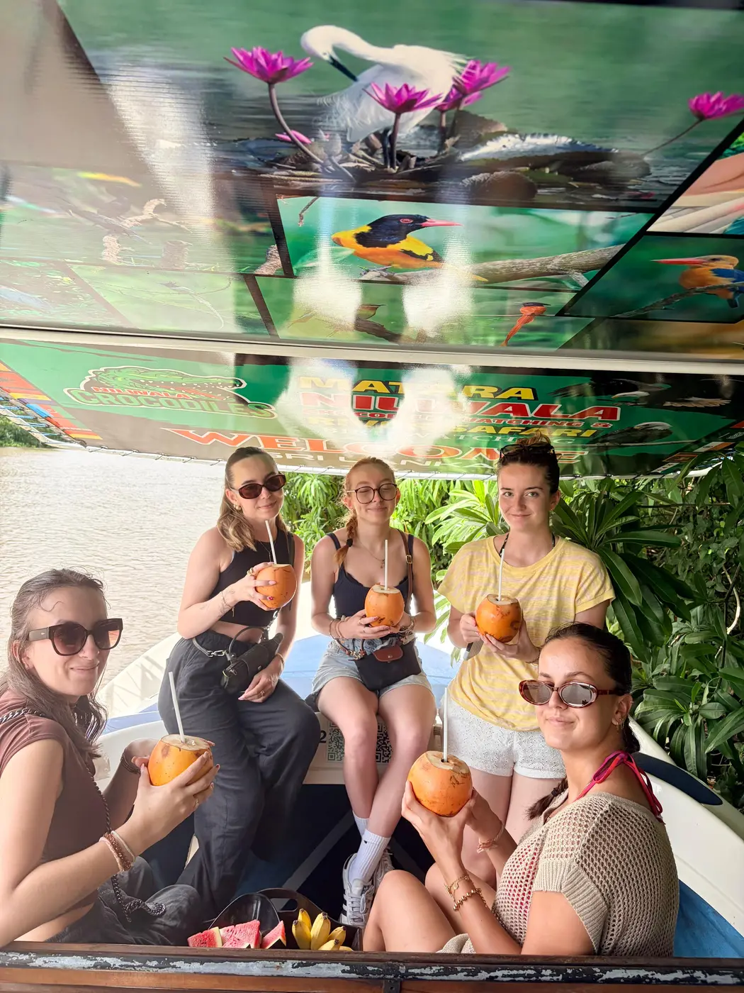 Guests sharing king coconuts under the boat canopy on the Nilwala