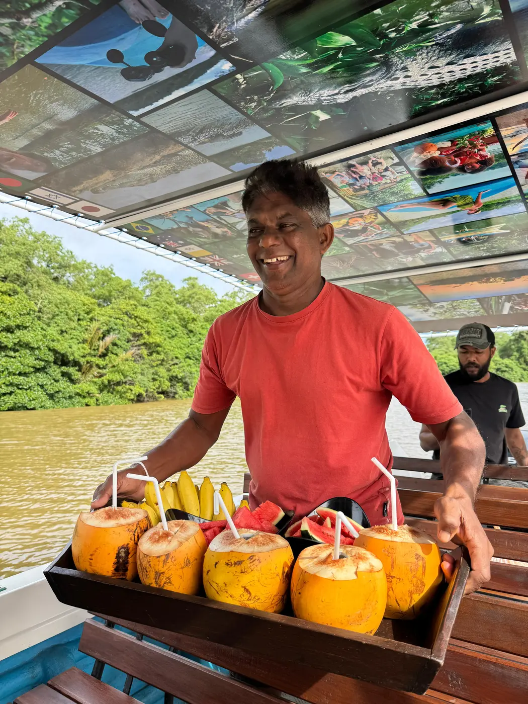 Skipper presenting a tray of king coconuts, watermelon and banana to guests