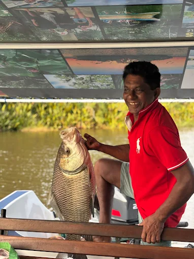 Local skipper holding a river fish on the boat